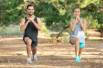 Wall Mural - Young man and woman doing exercises in park