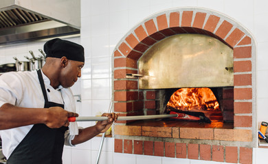 Wall Mural - Chef baking pizza in wood fired oven