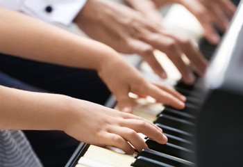 Wall Mural - Young man and little girl playing piano, closeup