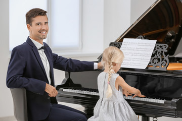 Poster - Young man teaching little girl to play piano indoors