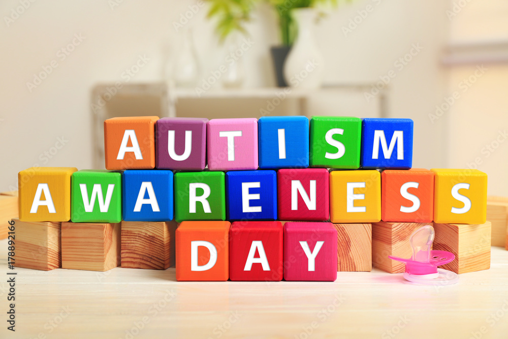 Cubes with text AUTISM SPECTRUM DAY on table