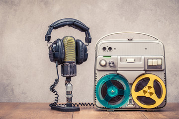 Poster - Retro reel to reel tape recorder circa 60s, microphone and headphones on wooden table front concrete wall background. Vintage style filtered photo