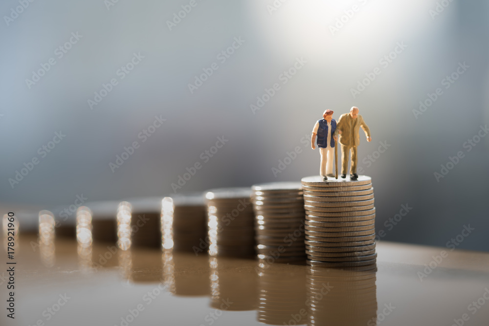 Concept of retirement planning. Miniature people: Old couple figure standing on top of coin stack. - obrazy, fototapety, plakaty 