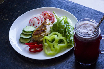 A fresh meal of chicken fillet with vegetables and tasty juice on a dark wooden background