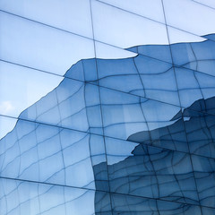 Wall Mural - part of geometrically shaped modern glass building with reflections of blue sky and glass wall