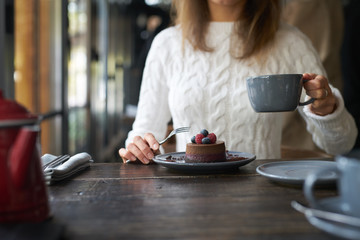 Wall Mural - Girl eating chocolate dessert brown with big cup of coffee