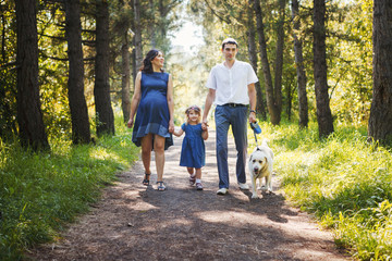 Wall Mural - Happy family with dog walking in the Park