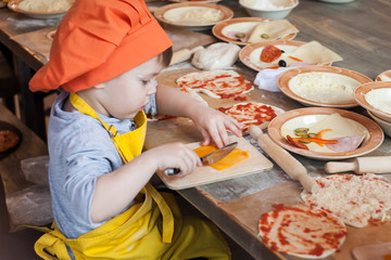 Little cook. Children make pizza. Master class for children on cooking Italian pizza. Young children learn to cook a pizza. Kids preparing homemade pizza