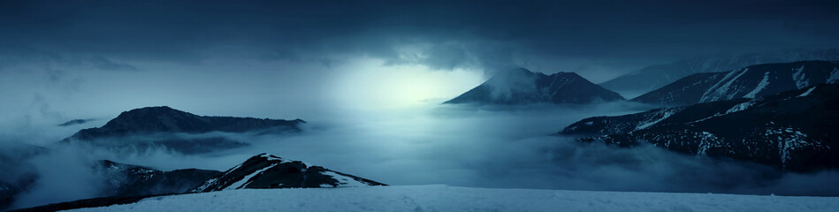 Fantasy photo of a mountains in the mist at evening. White lights. Magic and scenic landscape photo