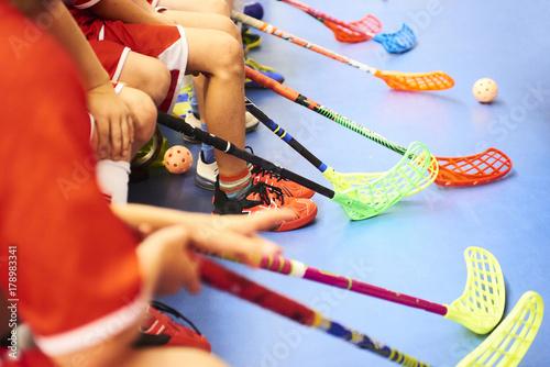 Children playing floorball. Boys holding floor ball sticks resting on the bench during a match