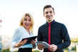 © Ivan Traimak - Couple of businessmen, good looking brunette man and attractive blonde woman stand on the roof and look in tablets