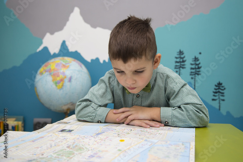 Plakat Kaukaski chłopiec czyta mapę