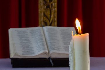 A bible open on a table next to a candle