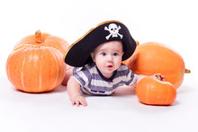 Cute Baby With A Pirate Hat On His Head Lying On His Stomach On A White Background Including Pumpkins On Halloween