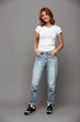 © Drobot Dean - Full length photo of cute brunette woman with hands in her pockets wearing trendy mom jeans and white tshirt, looking at camera