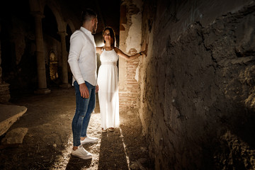 Hombre y mujer enamorados en un templo antiguo iluminados por la luz del sol al atardecer