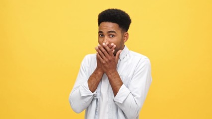 Sticker - Shocked african man in shirt covering his mouth and looking at the camera over yellow background