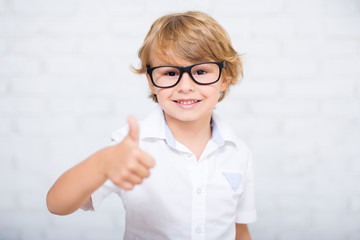 Wall Mural - close up portrait of cute little boy in glasses thumbs up