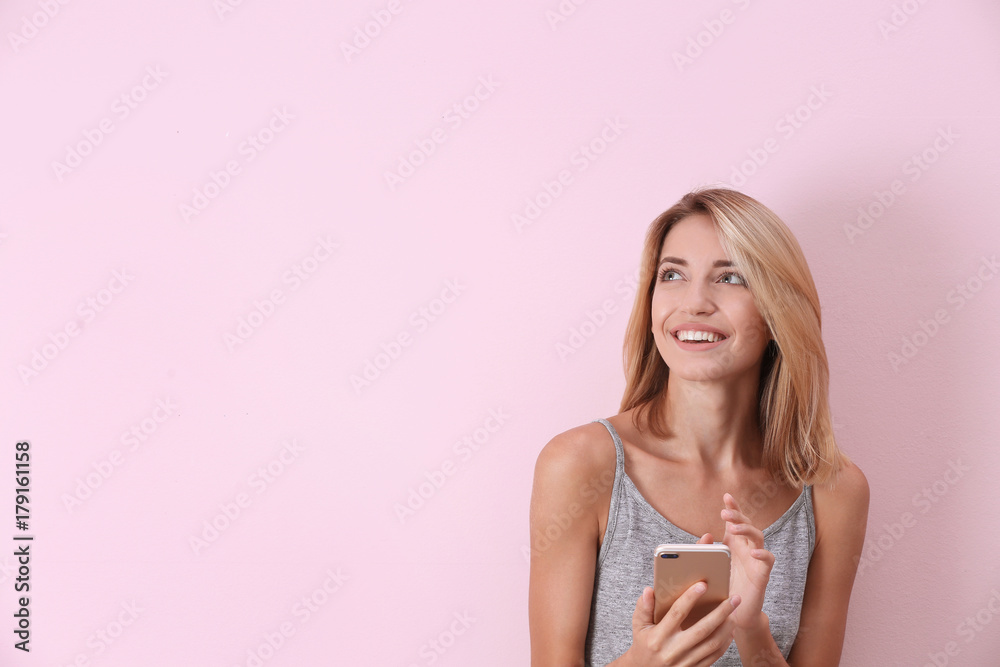 Beautiful young woman with mobile phone on color background