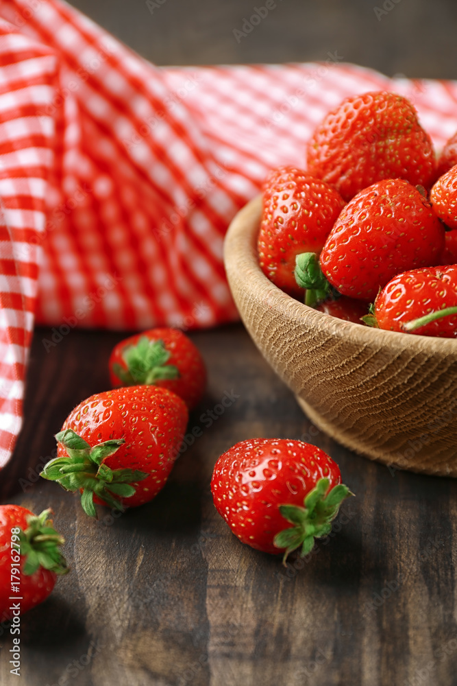 Bowl with fresh strawberries on wooden table