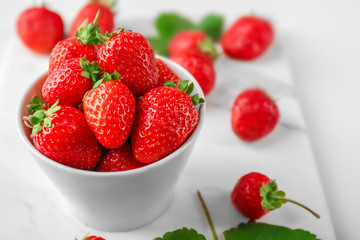 Wall Mural - Bowl with fresh strawberries on table, closeup