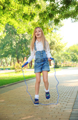 Wall Mural - Cute little girl jumping rope in park