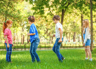 Wall Mural - Cute little children jumping rope in park