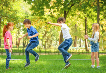 Wall Mural - Cute little children jumping rope in park