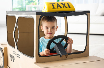 Canvas Print - Little boy playing with cardboard taxi in light room