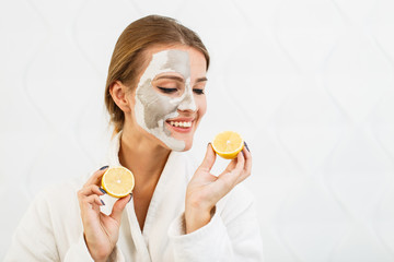 Lovely, smiling girl having fun with two halves of lemon, indoor shot in the white background