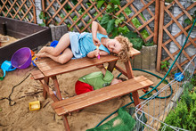 Mała Dziewczynka Leży Na ławce Na Placu Zabaw Dla Dzieci.