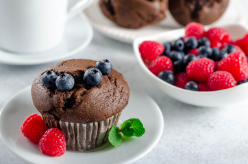 Wall Mural - One chocolate muffin with fresh tasty raspberries and blueberries, horizontal image