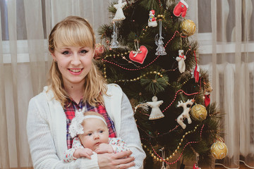 Portrait of happy mother and adorable newborn baby on Christmas evening