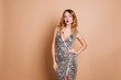 Elegant caucasian woman with curly hairstyle posing with kissing face expression at chrismas party. Charming birthday girl in sparkle dress standing in confident pose on light background.