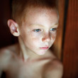 © Dina Marie Photography/Stocksy - Portrait of young boy no shirt, red hair, blue eyes & freckles. His head is turned to the side showing a three quarter view of face.