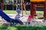 Fototapeta  - Rodzeństwo dzieci bawi się na planu zabaw w jesienny słoneczny dzień.