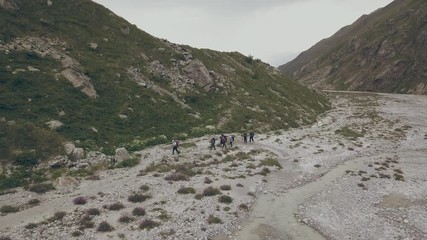 Wall Mural - aerial view tourist group walking on mountain trail on background mountain peaks