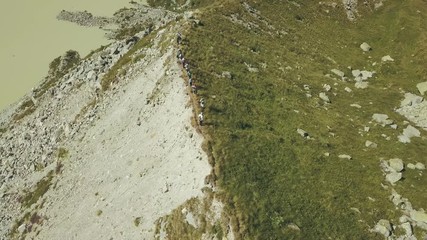 Wall Mural - sky view hiking group walking on mountain edge. lake view and mountain peaks