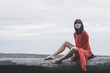 © Ania Boniecka/Stocksy - A woman sitting on a tree trunk at the beach