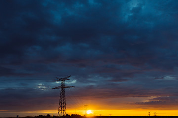 high voltage power lines and transmission towers at sunset. poles and overhead power lines silhouett