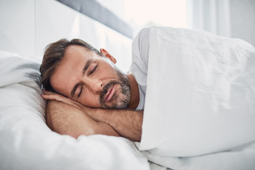 Peacefulness concept. Handsome man sleeping in bed