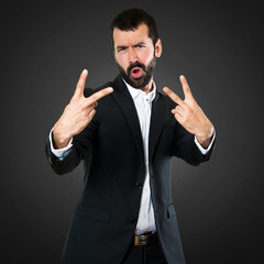 Handsome businessman making victory gesture on black background