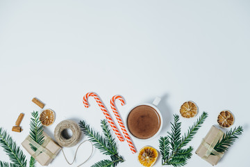 Wall Mural - Christmas background with fir tree, hot chocolate, gift, candy canes on white board. Top view with copy space