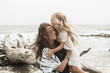 © Marc Romanelli/Blend Images - Caucasian mother hugging daughter near driftwood on beach