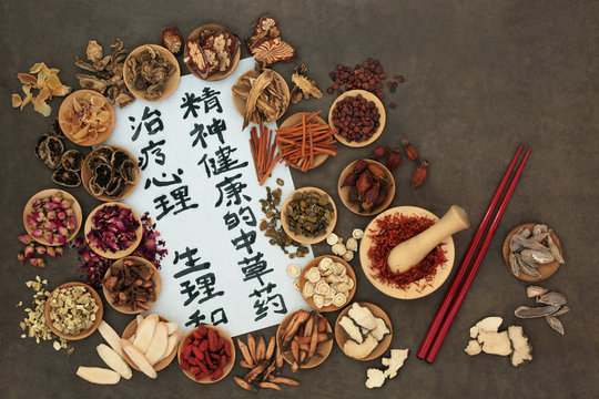 Chinese herbs used in alternative herbal medicine with calligraphy script on rice paper. Translation reads as traditional ancient chinese medicine to heal mind, body and spirit.