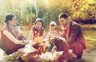 Poster - happy family roasting marshmallow over campfire