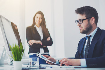 Image of two young businessmen working together on project at office