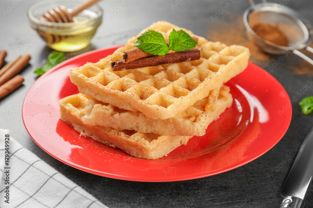 Plate with delicious cinnamon waffles on table
