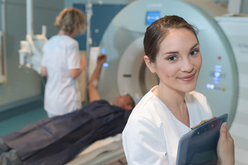 smiling female radiologist with colleagues standing by mri machi