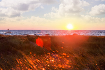 Wall Mural - Sunset over the lake with red glowing flares of light